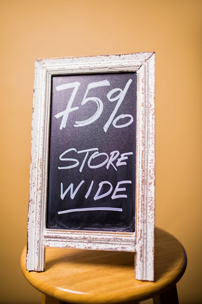 Home Chalkboard displaying 75% store wide discount offer on a wooden stool with orange backdrop.